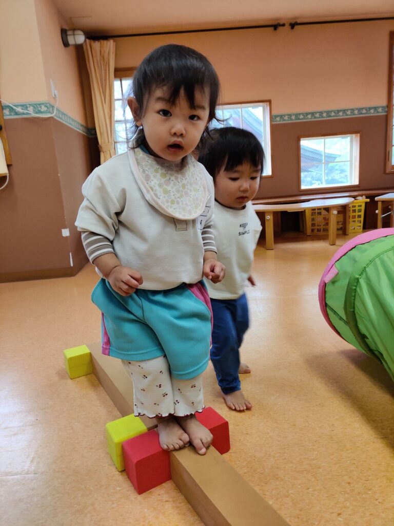 そろりそろり、平均台の上で自分の力を確かめる足元(すみれ組・1歳児クラス)