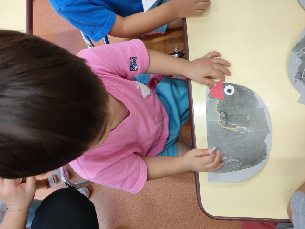 両面テープでダンゴ虫の目と口をそっと貼る、いちご組さん(2歳児クラス)の小さな指先