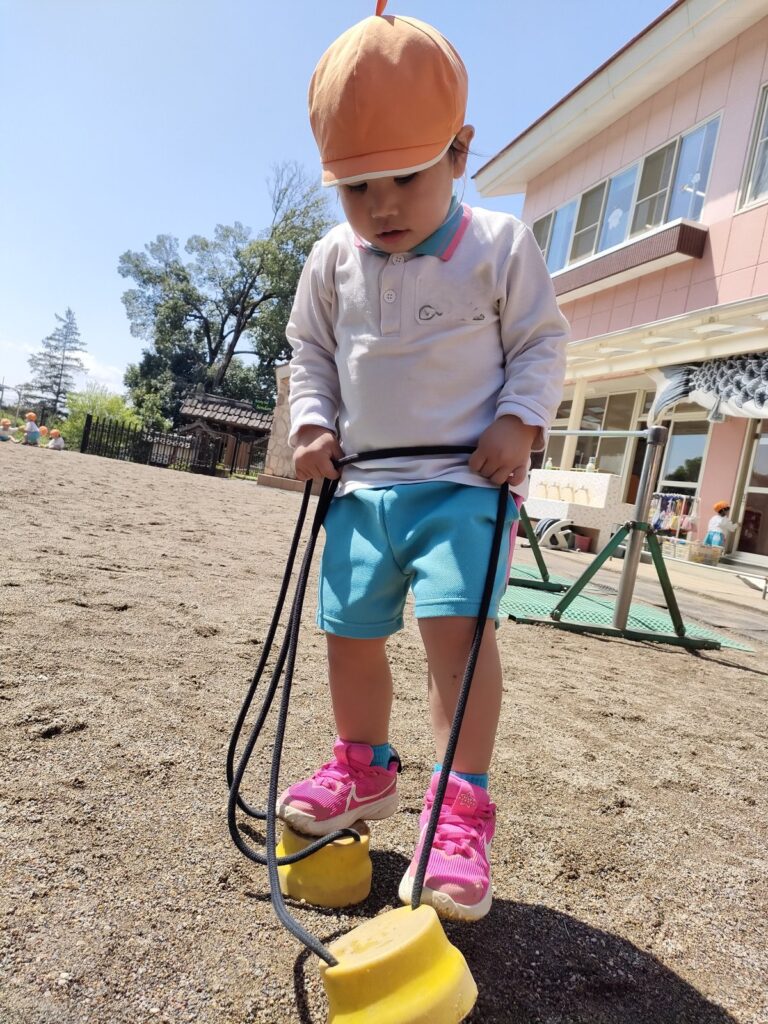 パカポコの台に自分の力で乗れて、ぱっと振り返るいちご組さん(2歳児クラス)