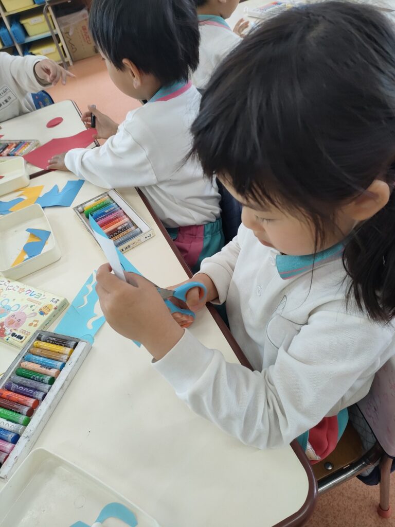 大きなこいのぼりに、一枚ずつ鱗を貼っていくさくら組さん(5歳児クラス)