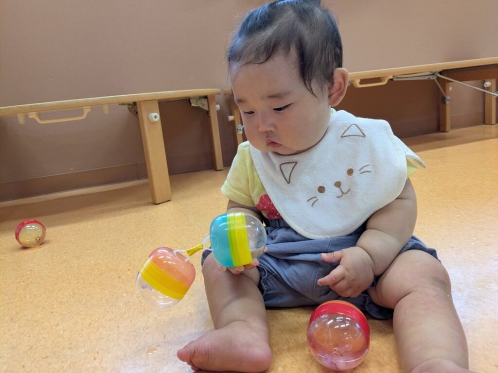 音の鳴る玩具に、じっと見入るひよこ組さん(0歳児クラス)