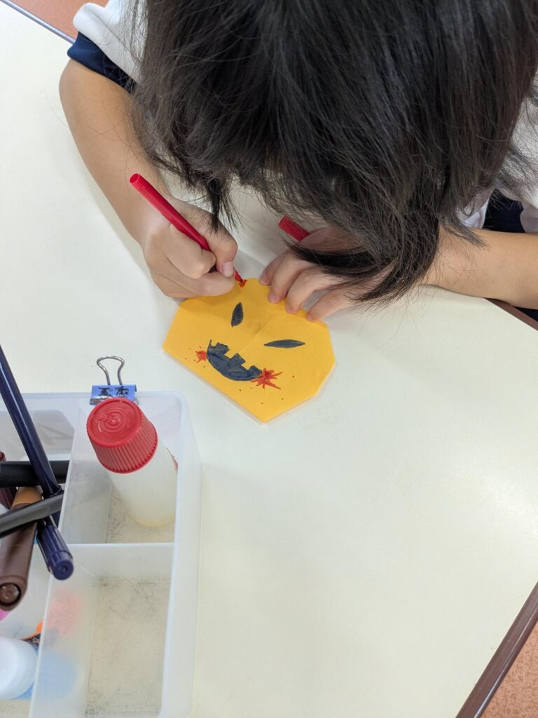 折り紙の飾りに自分の顔を描き入れる手元